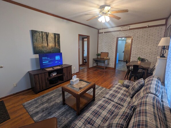 A living room with a television, sofa, coffee table, and a ceiling fan.