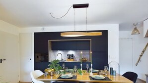 Een moderne eethoek met een houten tafel, donkere stoelen en een hanglamp.