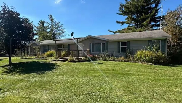 Une maison à deux étages, dotée d’une pelouse bien entretenue et d’une antenne parabolique sur le toit.