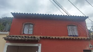 A red building with two windows, a brown door, and a white lower section.