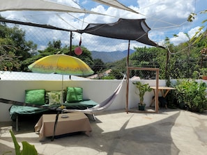 A hammock, a table with a chair, and a potted plant in an outdoor patio area. - Castillo De Los Gigantes (Antigua Guatemala)