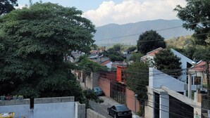 A residential area with houses, a tree, and a car parked on the street. - Castillo De Los Gigantes (Antigua Guatemala)