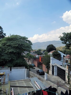 A residential area with houses, a tree, and a car parked on the street. - Castillo De Los Gigantes (Antigua Guatemala)