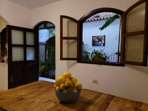 A room with a wooden table, a bowl of lemons, and a window with a painting. - Castillo De Los Gigantes (Antigua Guatemala)