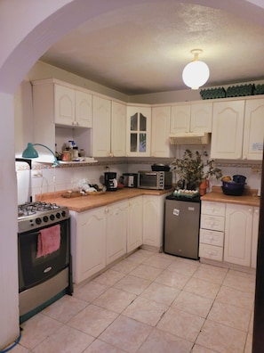 A kitchen with white cabinets, a gas stove, a microwave, and a refrigerator. - Castillo De Los Gigantes (Antigua Guatemala)
