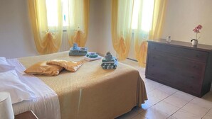 Una habitación de hotel con cama, cómoda y ventana con cortinas amarillas.