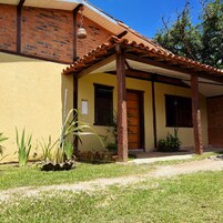 Un edificio amarillo con fachada de ladrillo, puerta de madera y un porche cubierto con techo de tejas.