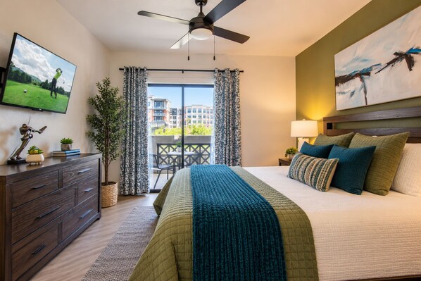 A hotel room with a bed, a dresser, a ceiling fan, a TV, and a balcony with curtains. - Heated Pool | Hot Tub | Walk to Kierland | NearTPC (Scottsdale)