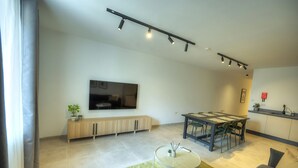 A modern living room with a flat-screen TV, a dining area with a table and chairs, and a kitchen area with a sink and countertop. - Chic, bright and modern 3 bedrooms KBAS1-1 (Gzira)