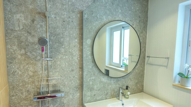 Een moderne badkamer met douche, wastafel en spiegel.