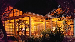 A modern house with large glass windows, surrounded by lush greenery. - IGWARA LODGE (Karuma)