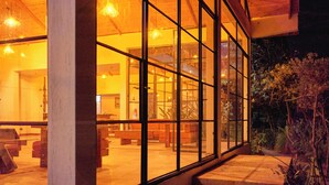 A building with large glass windows, wooden interior, and a staircase leading to an upper level. - IGWARA LODGE (Karuma)