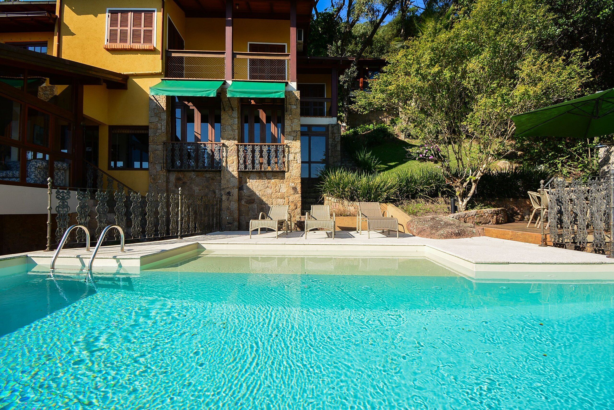 A swimming pool with lounge chairs and a stone building with balconies.