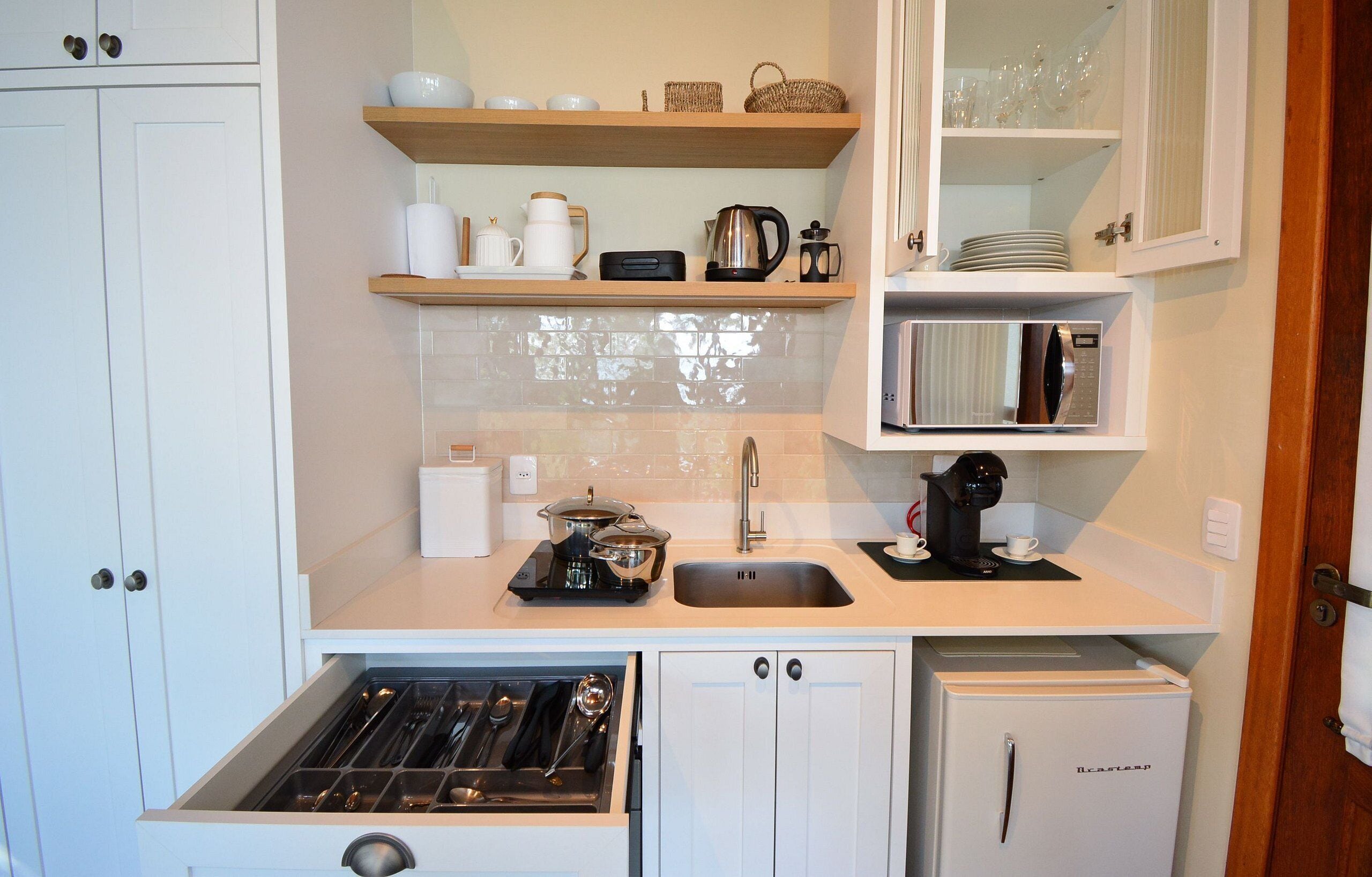 A compact kitchen with a built-in stove, a sink, a microwave, and a refrigerator.