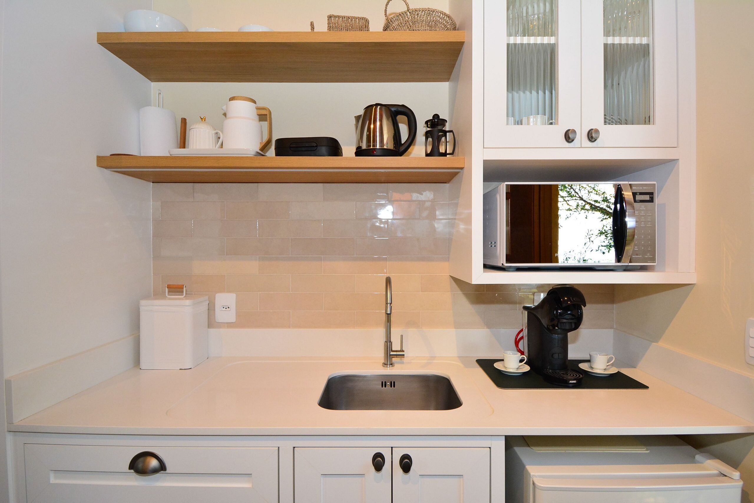 A kitchen with a sink, a microwave, and a coffee maker on the countertop.