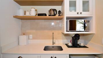 A kitchen with a sink, a microwave, and a coffee maker on the countertop.