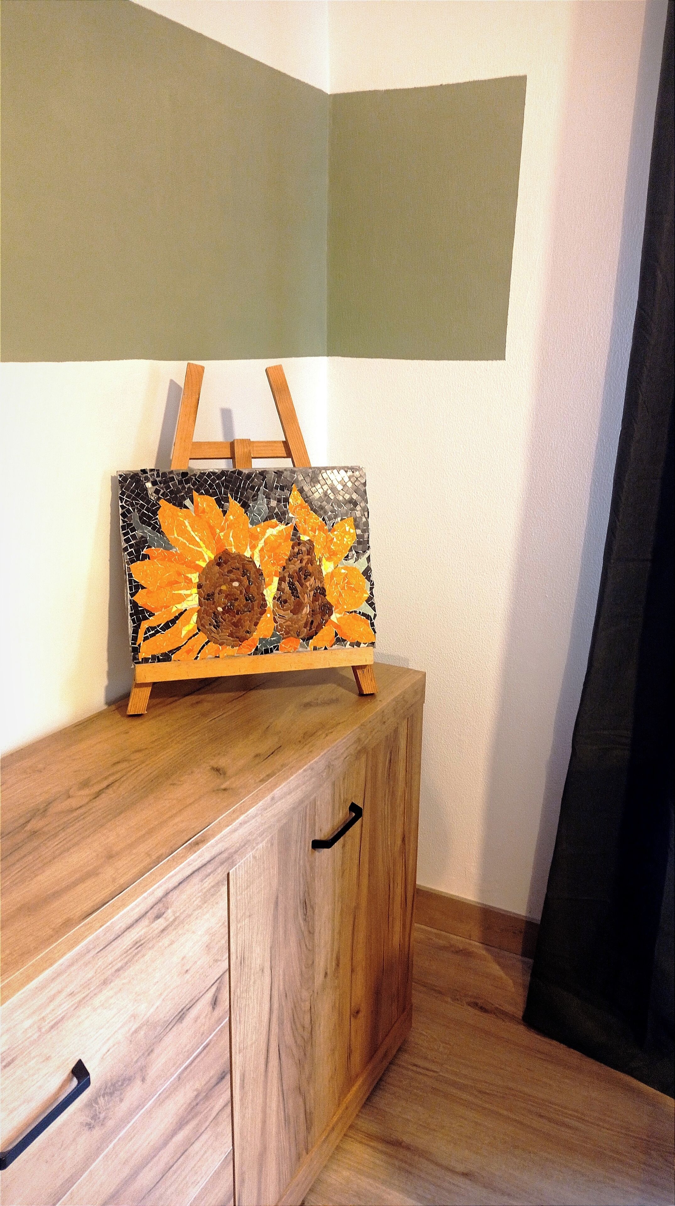 Ein Holzkabinet mit einem Mosaikbild von Sonnenblumen auf der Oberseite.