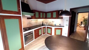 A kitchen with wooden cabinets, a stove, and a dining area with a table.