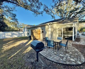A backyard with a barbecue grill, patio furniture, and a covered outdoor seating area.