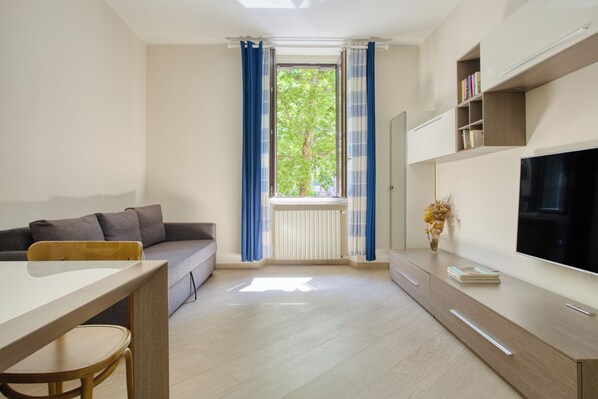 Una sala de estar moderna con un sofá, una mesa de comedor y un televisor.