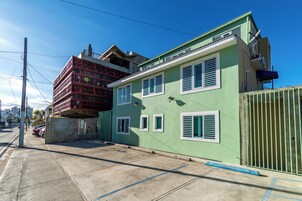 Un edificio de dos pisos con fachada verde y contraventanas blancas.