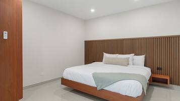 Un dormitorio moderno con estructura de cama de madera, ropa de cama blanca y cabecera de madera.