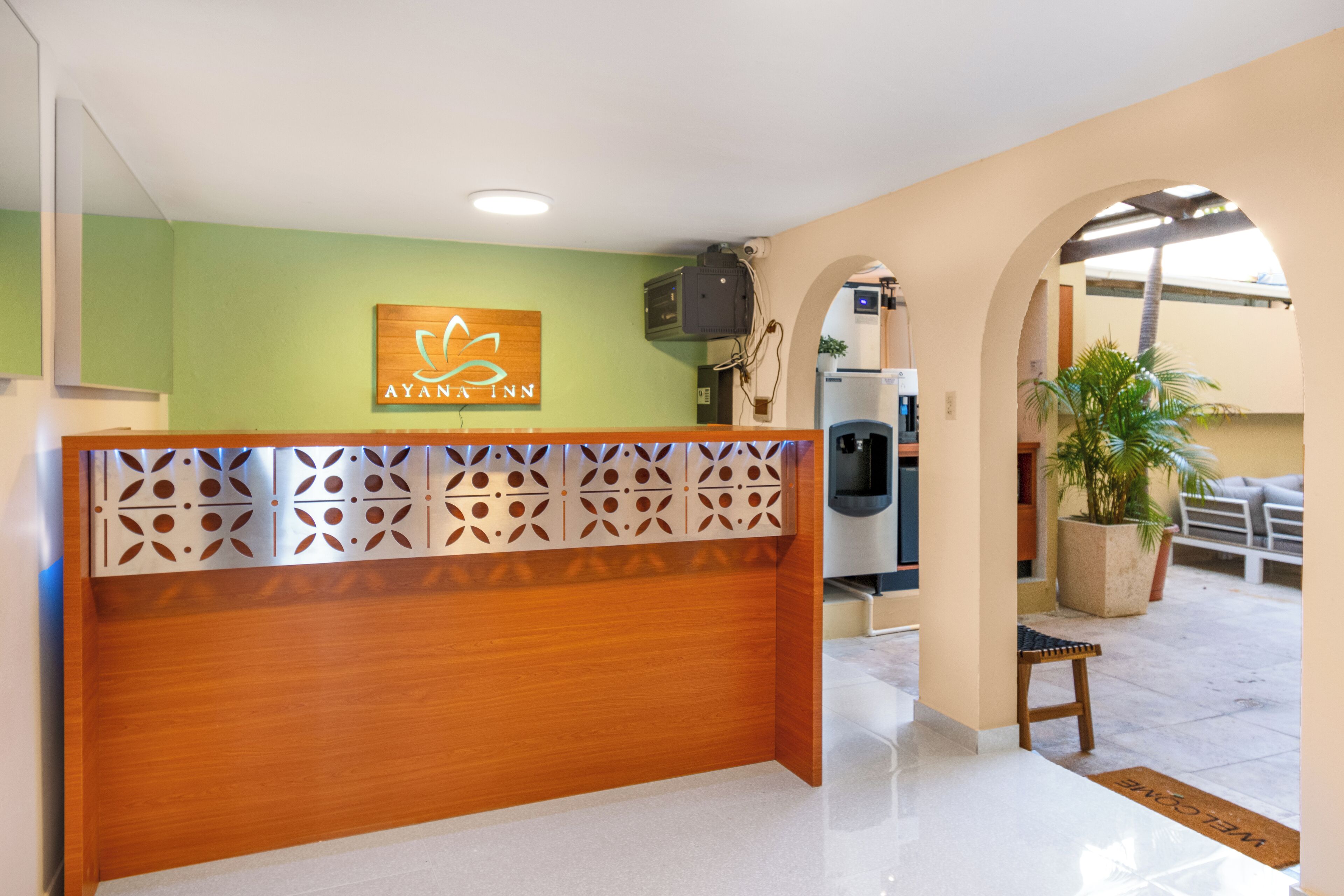 A reception area with a wooden desk, a logo on the wall, and a coffee machine.