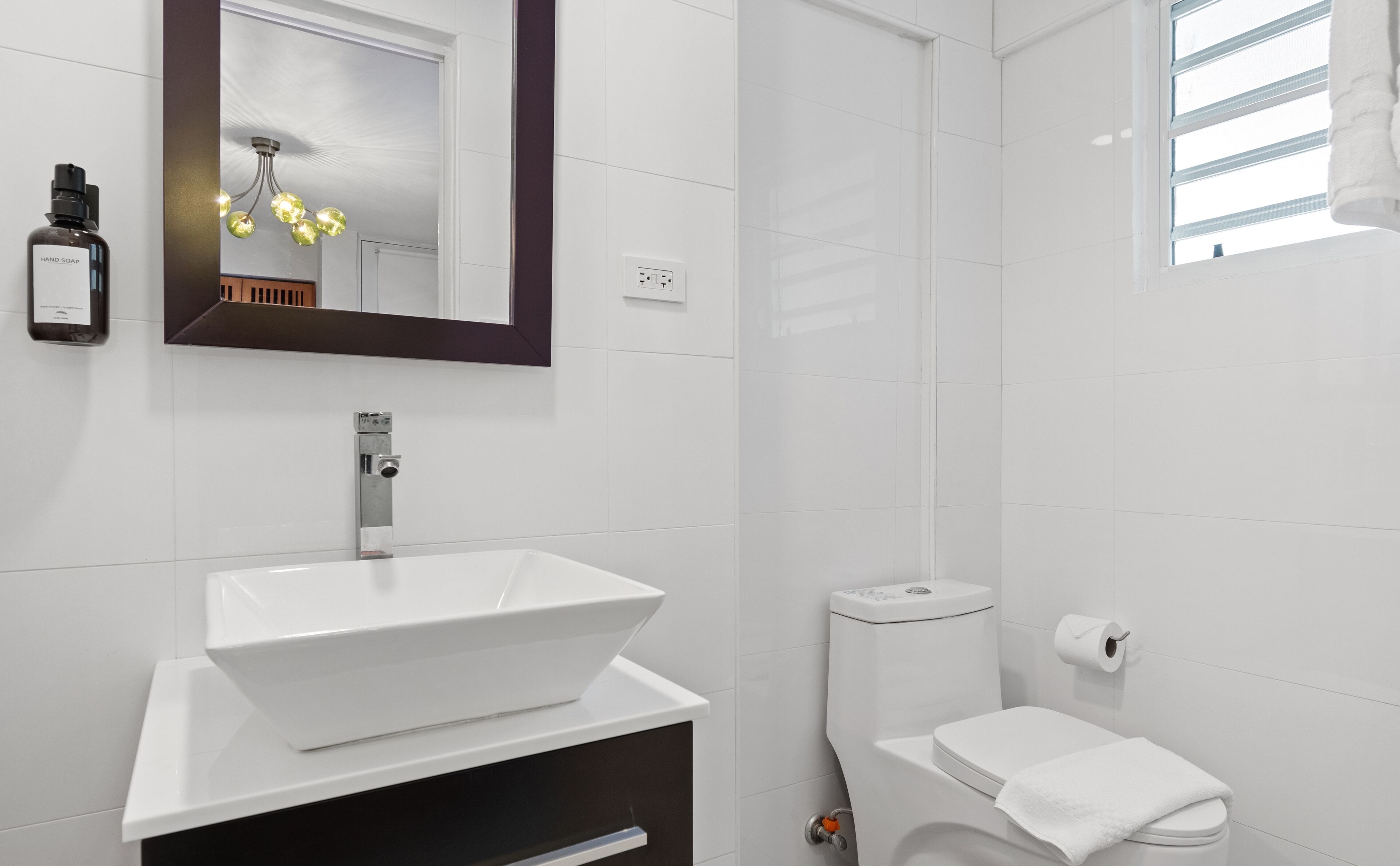 A modern bathroom with a white sink, a toilet, and a shower.