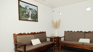 A room with two wooden sofas, a small table, a vase with pampas grass, and a painting on the wall. - Hotel Cascada el Garruño (Calvillo)