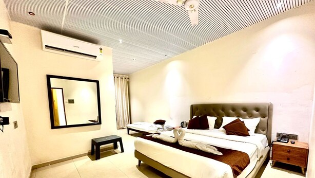 Quarto de hotel com uma cama, mesa de cabeceira, espelho e ar condicionado.
