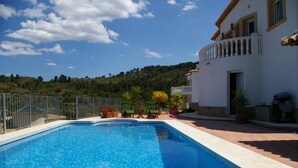 A swimming pool with a view of a hillside, a fenced area with lounge chairs, and a building with a balcony. - 6 Guests - Private Pool - 3Br Villa - Amazing View (Orba)