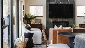 A modern living room with a large TV, wooden ceiling, and a fireplace. - The Squire at Dunlap Ridge (Rockbridge)