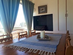A dining area with a wooden table, blue and beige woven rug, and a candle centerpiece. - Golfbeach Luxury Self Catering Apartment (Cape Town)