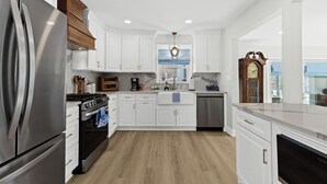 Une cuisine moderne avec des armoires blanches, des appareils électroménagers en acier inoxydable et un plafond en bois.