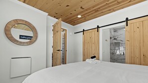 Une chambre à coucher avec un grand lit, un miroir rond, une porte coulissante et un radiateur.
