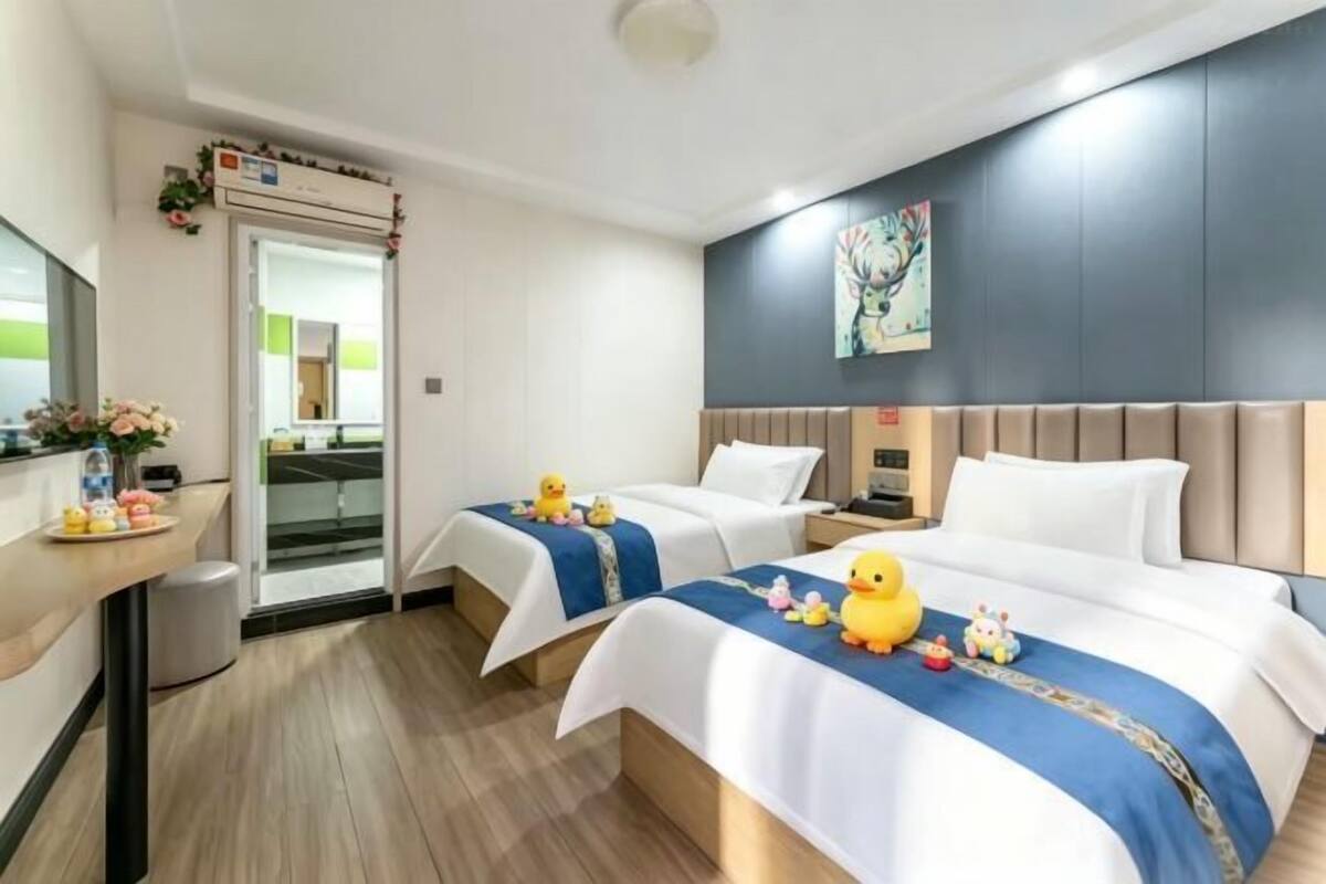 Une chambre d’hôtel avec deux lits, un bureau, un miroir et une fenêtre.