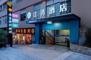A hotel entrance with a blue awning, a staircase leading to the entrance, and a sign with Chinese characters.