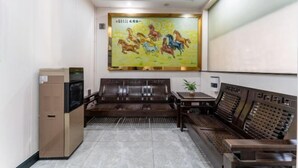 A hotel lobby with a large mural, seating area, and a coffee machine. - Jiangtao Hotel Guangzhou (Guangzhou)
