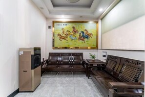 Un hall d’hôtel doté d’une grande fresque murale, d’un espace salon et d’une machine à café.
