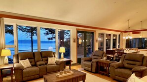 A spacious living room with large windows, a wooden coffee table, and leather sofas.