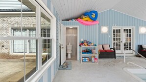 Een zwembad met een jacuzzi, een plank vol speelgoed en een deur naar een badkamer.