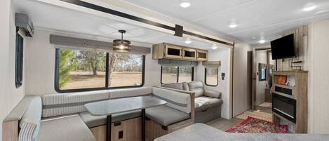 Ein modernes Wohnmobil-Interieur mit Küchenzeile, Sitzgelegenheiten und Fernseher.
