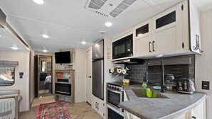 Una cocina compacta con microondas, estufa, refrigerador y pileta.