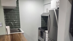 Eine moderne Küche mit Holzarbeitsplatte, Edelstahlgeräten und dunkelgrau gefliestem Rückspritzschutz.