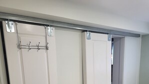 Ein Schlafzimmer mit einem Bett, einem Kleiderschrank mit Ganzkörperspiegel und Holzboden.