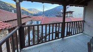 A balcony with a view of red-tiled buildings and a mountain in the background. - Fani's house (Platanos)