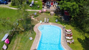 An aerial view of a swimming pool surrounded by lounge chairs and a deck area with a building in the background. - 14-bedroom resort in tranquil Paupack. 1885 Farm & Guest House with Game Room! (Paupack)