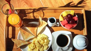 A breakfast tray with toast, scrambled eggs, a cup of coffee, a jug of juice, and a bowl of fruit. - Muyuterra (Moyobamba)