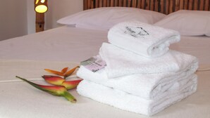 A neatly made bed with white linens and a folded towel on top. - Muyuterra (Moyobamba)