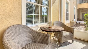 Ein Balkon mit Korbmöbeln und Blick auf ein Gebäude mit einem Balkon.